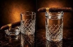 Pair of cut-crystal double old fashioned cigar glasses with built-in cigar rests, cigars resting on the rims