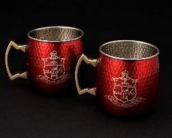 Pair of hammered red Moscow mule mugs with brass handles and an etched crest