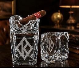 Crystal cigar glass with diamond insignia beside a matching square crystal ashtray cover, cigar resting