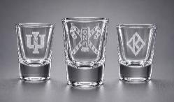 Three etched shot glasses showing a crest, a Psi design and a floating-K diamond design