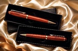 Wide rosewood ballpoint pen with chrome trim shown in a black-lined case on champagne satin